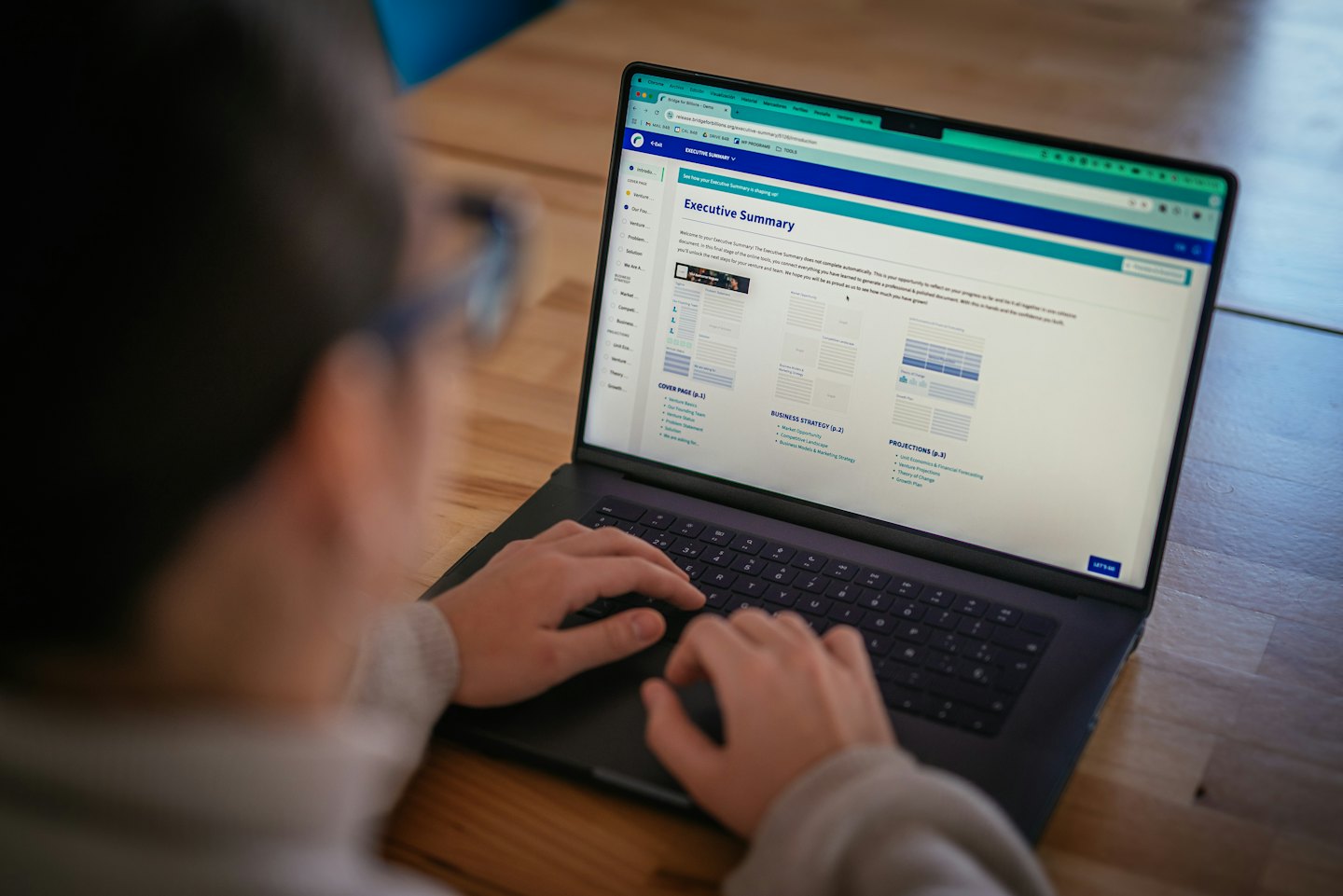 Professional typing an executive summary on a laptop computer.